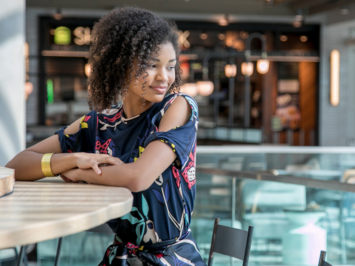 A young woman sits at a table at Aventura Mall