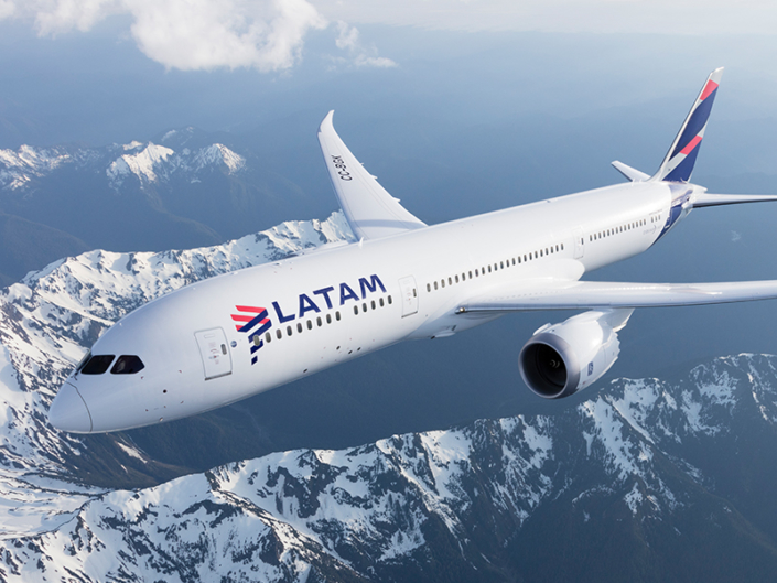A LATAM Airlines plane flies above snow-capped mountains